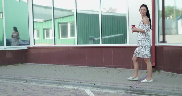 Happy Lady with a Cup of Beverage Walks at Office Centre Turns and Rejoices