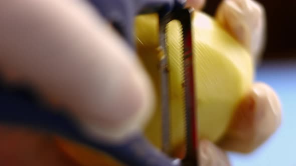 The cook is peeling potatoes. A man peels raw fresh potatoes with a manual potato peeler. Peeled pot