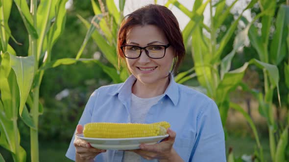 Middleaged Woman with Boiled Corn in Plate