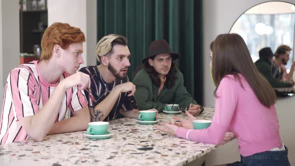 Young Retro Woman Sharing with Friends in Vintage Cafe Talking As Shocked Men Taking Off Sunglasses