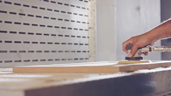 Slow motion of a worker polishing a cabinet door in a furniture factory