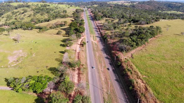 A highway through the countryside on a summer day - pull back tilt up aerial flyover