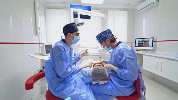 Dentist and patient in dentist office. Dentist treating patient teeth while working in clinic