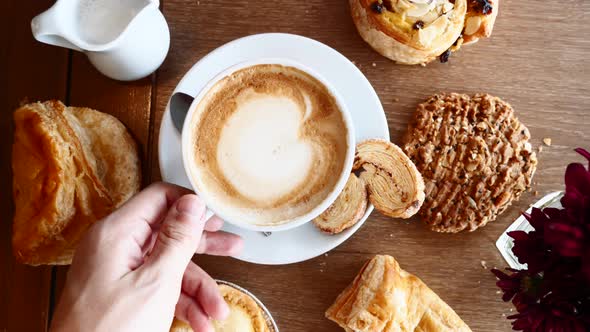 Man Hand Take Cup of Coffee on Breakfast with Croissants on Wooden Table in Cafe