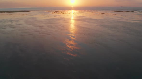 Drone Over Low Tide Beach Towards Sunrise Over Sea