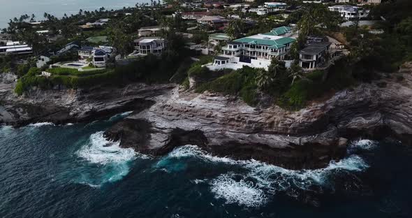 Drone shot of a cliffside beach that has both amazing houses and a nice views of the waves crashing