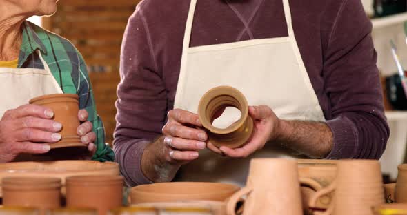 Male and female potter interacting while examining a pot