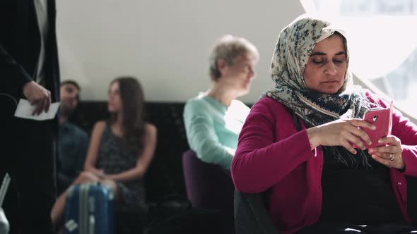 Islamic Female waiting in airport lounge on mobile phone