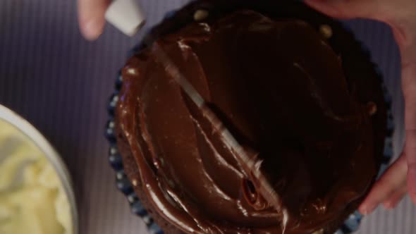 Topping a cake with thick chocolate frosting - top down view