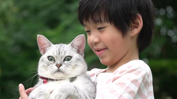 Cute Asain Child Playing With British Cat In The Park 