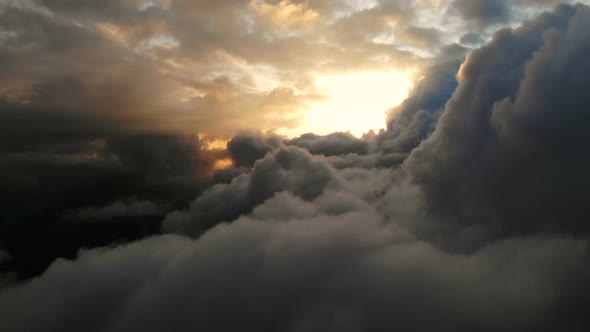 Aerial View Flying Through Cumulus Thunderclouds at Sunset. Gold Colored Sunset Cloudiness in High