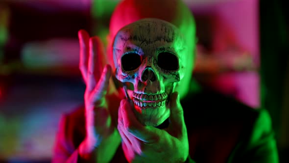 Old Human Skull in Hands of Strange Man in Neon Lights Mysterious Portrait