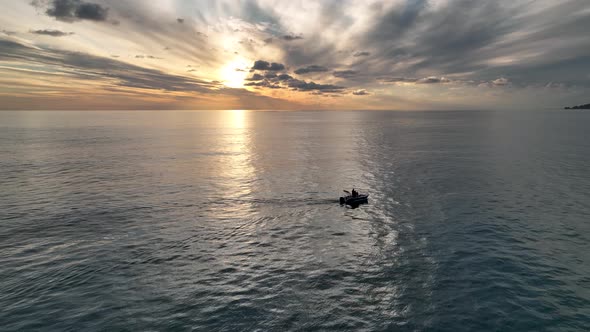 Fishing boat far out to sea at sunset