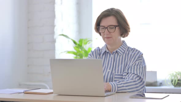 Senior Woman Celebrating Online Success in Office