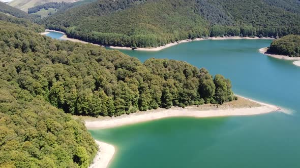 Aerial horizontal footage of a lake in a green natural environment with mountains in the Spanish Pyr