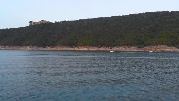 low side pan of two boars driving along the cliffs of lake travis. Shot on 9/10/20 in Austin Texas.