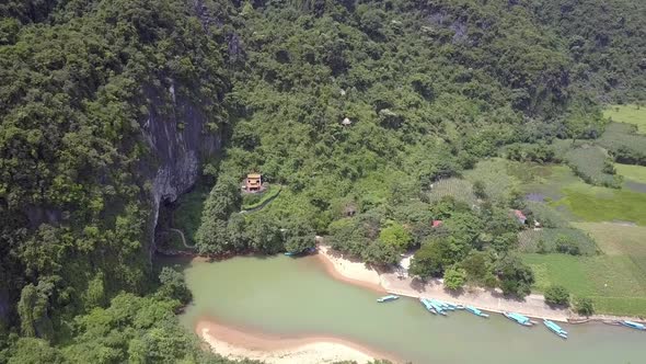 Aerial Motion Above Calm River Running From Mountain Grotto