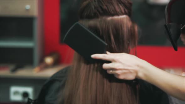 Shot of the Hairdresser's Hands Who Dries Hair with a Hair Dryer and Comb