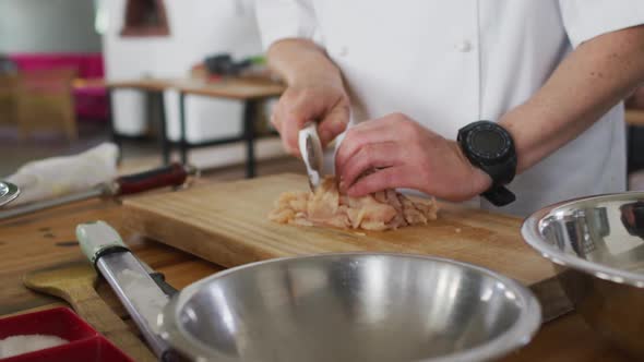 Caucasian male chef kutting meat on a kitchen table