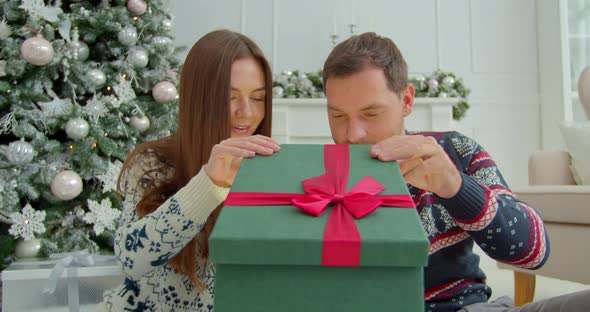 Happy Couple Opening Magical Present Boxes Near Christmas. Man and Woman Family Celebrating