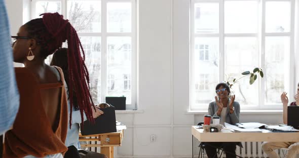 Side View Smiling Young Business Woman Entering Modern Office Holding a Box, Colleagues Cheering Up