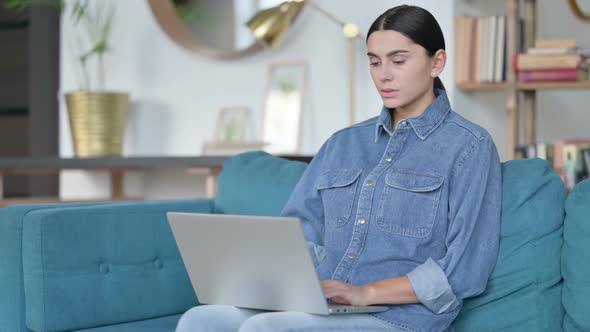 Laptop Work By Latin Woman with Neck Pain on Sofa