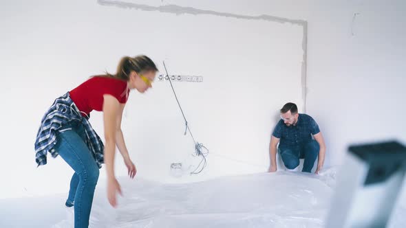 Couple Covers Floor with Foil Near White Wall in Own House