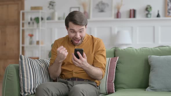 Young Man having  Success on Smartphone at home