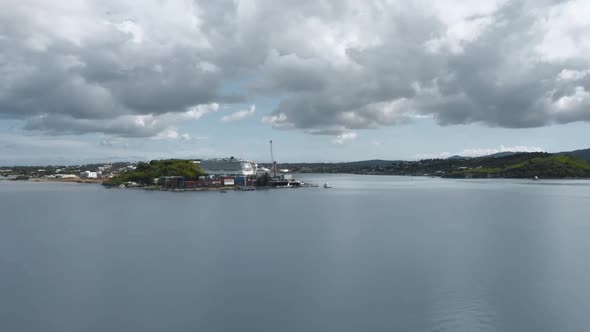 Drone is approaching a bay with a cruise ship. Hilly island. A lot of clouds. Aerial shot in Antigua