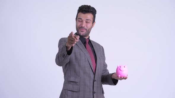 Happy Bearded Persian Businessman Holding Piggy Bank and Giving Thumbs Up