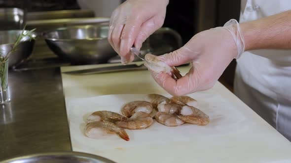 Closeup of a Chef Cutting a Shrimp with a Knife in the Restaurant Kitchen