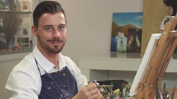 Bearded Handsome Cheerful Artist Smiling To the Camera While Working at His Studio