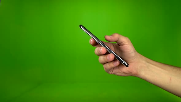 Male Hand Flipping Through a Touch Phone. Green Screen. Side View