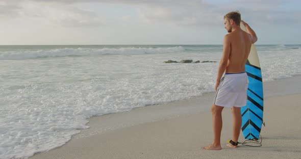 Man standing with surfboard at beach 