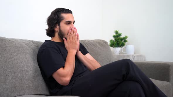 Disappointed Indian man sitting on the sofa
