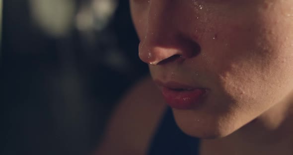 Macro Portrait of Sweaty Athlete Catching Breathes in a Dark Gym