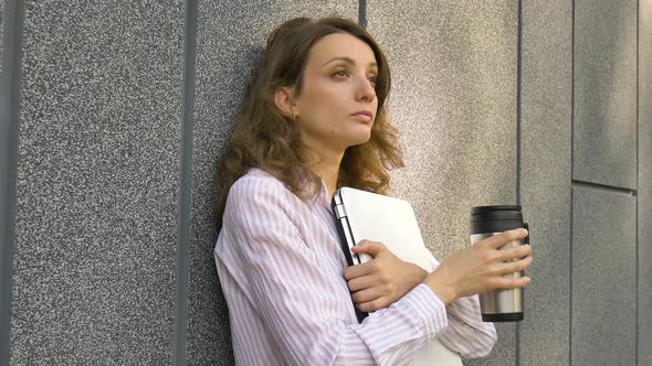 Female Portrait of Young Woman with Silver Laptop and Cup of Coffee Waiting for a Meeting Near Dark