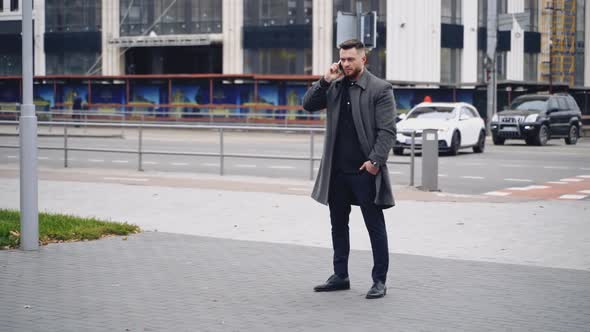 Young man talks on smartphone on street. 