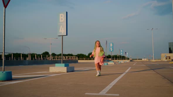 Child dancer express positive emotions using her body. Girl dancing at parking outdoor