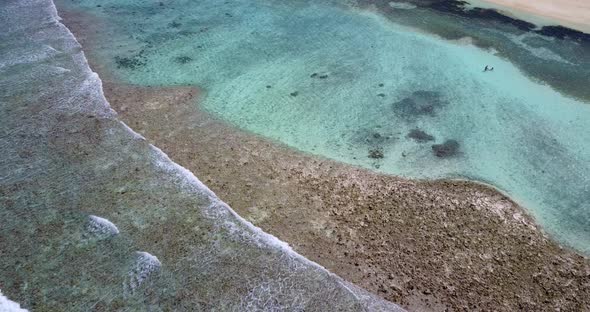 Daytime drone clean view of a sunshine white sandy paradise beach and blue sea background in colorfu