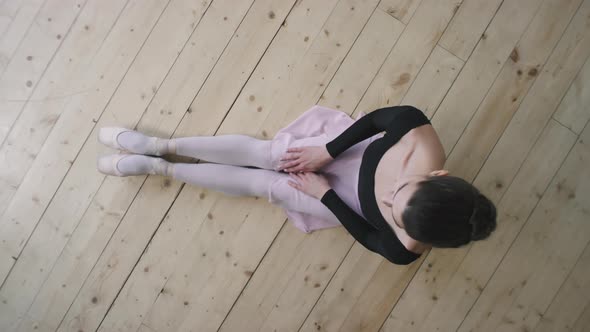 Top View Of Ballerina Sitting On Wooden Floor