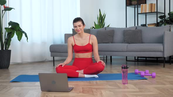 Smiling Fit Woman Sits on Yoga Mat Watch Distance Sport Education Lesson Course