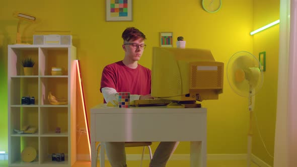 Young Man Is Sitting At Desk and Typing On Keyboard