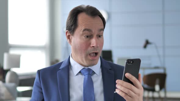 Businessman in Shock While Using Smartphone