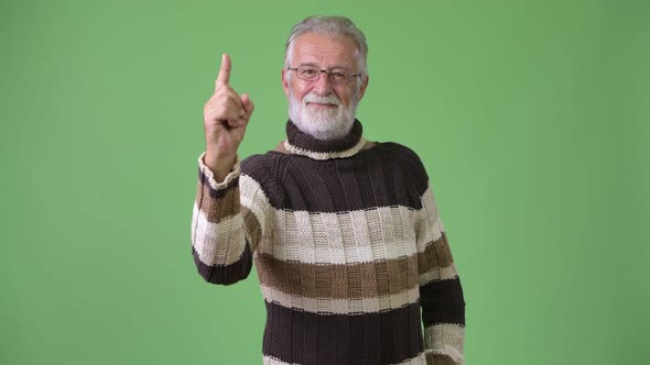 Handsome Senior Bearded Man Wearing Warm Clothing Against Green Background