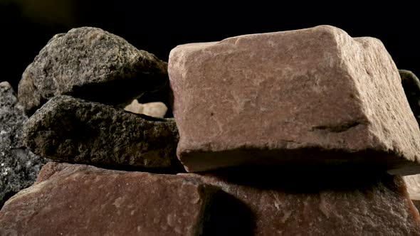 Pieces of Solid Rough Granite Stone Rotating Against a Black Studio Background