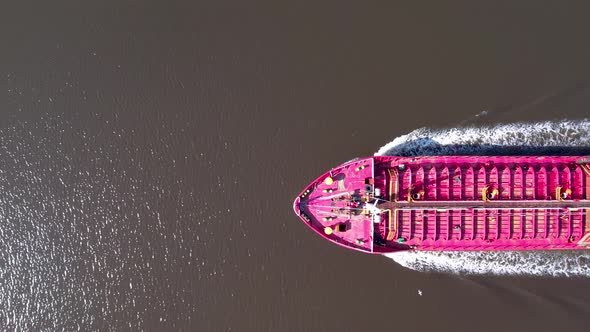 Aerial top down view of a red oil tanker floats.