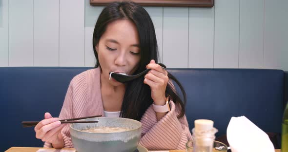 Woman eating noodles in restaurant