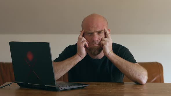 Smart working, covid 19. Tired man with headache, massaging his temples