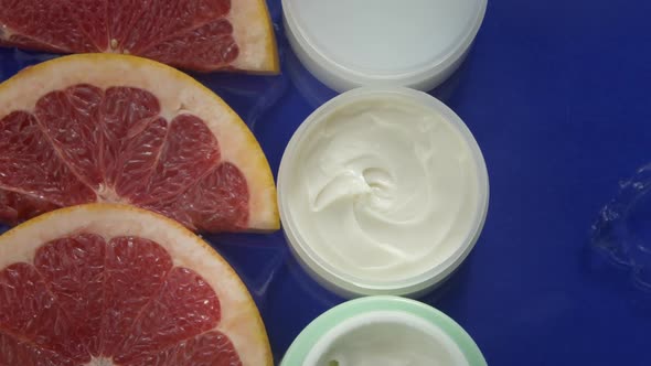 Cosmetic Jars with Moisturizing Cream and Fresh Grapefruit in Water Splash
